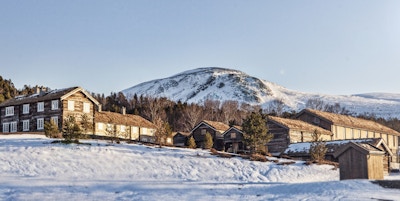 Gammel gård i snølandskap
 omkranset av fjell