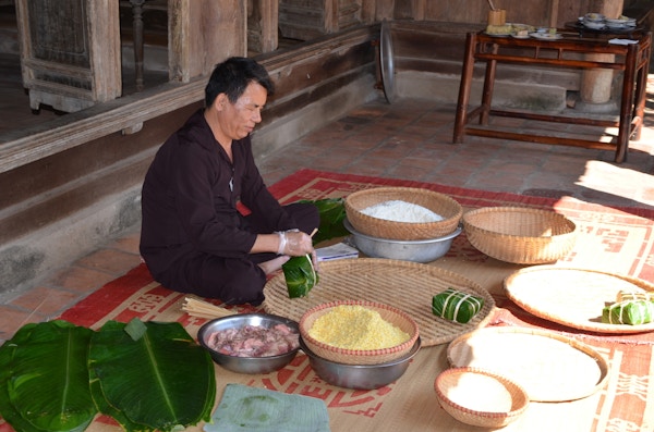 Vietnamesisk mann sitter på gulvet og jobber med mat.