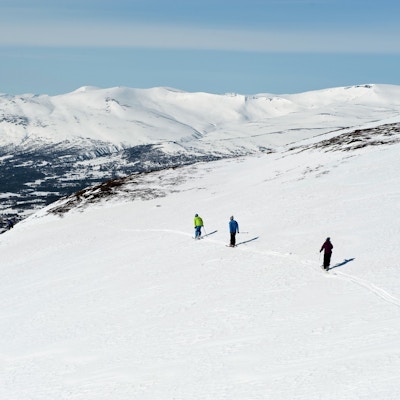 Fire personer, sett ovenfra, som er ute og går på ski i fjellet med sekk