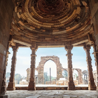 Jernsøylen gjennom klosterkolonnene ved Quwwat ul-Islam-moskeen i ruinene av Qutb Minar-komplekset i New Delhi, India.