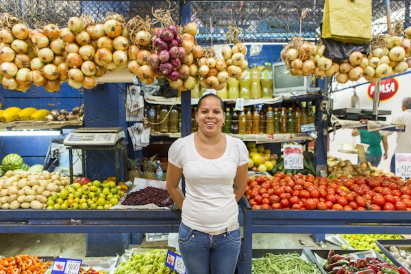 En dame som står og selger alle mulige grønnsaker på markedet