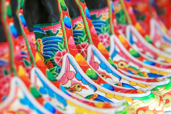 Nærbilde av tradisjonelle bhutanesesko i Thimphu sentrum, Bhutan. Kongedømmet Bhutan ligger fast i det østlige Himalaya, Thimphu er dens hovedstad og største by, mens Phuntsholing er dets finanssenter. Statssjefen er kongen av Bhutan, kjent som "Dragon King". Riket er aldri kolonisert og sitter på den gamle silkeveien mellom Tibet, India og Sørøst-Asia. Bhutan er kjent for å være banebrytende med begrepet Gross National Happiness.