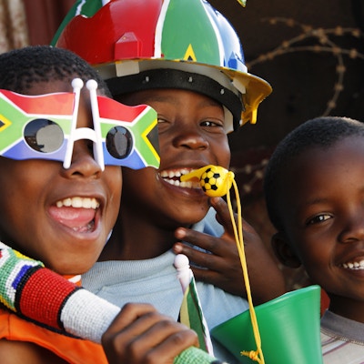 Tre afrikanske barn forbereder seg på å se verdensmesterskapet i fotball i Johannesburg, Sør-Afrika.