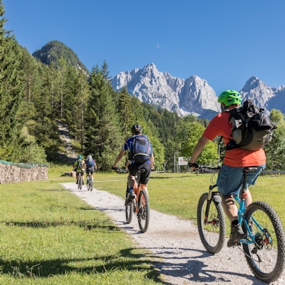 En gruppe terrengsyklister sykler mot fjellkjeden i de Julianske Alpene i nærheten av landsbyen Kranjska Gora. Området er veldig kjent for fotturer og sykling om sommeren og på ski om vinteren.