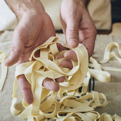 Nærbilde av hender som holder nylaget pasta.