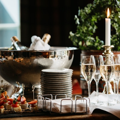 Tapas/fingermat på bordet sammen med bøtte med champagne og noen glass champagne