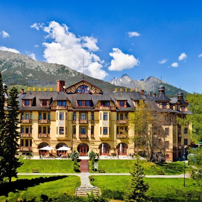 Fasade på hotell med hage i forkant og fjell i bakgrunnen