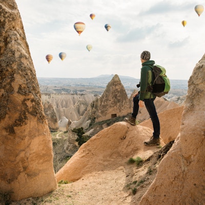 Mannlig turist som utforsker Cappadocia Red and Rose-dalene. Magiske sandsteinsfjell og hulelandskap nær Goreme.