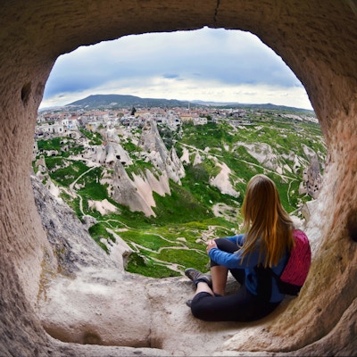Kvinne ser inn i det fjerne mot bakgrunnen av utrolig landskap med fjell, geologiske strukturer i Goreme, Cappadocia, Tyrkia