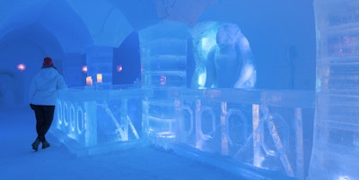 Mann som er kledd i vinterklær står ved baren laget av is inne i ishotellet