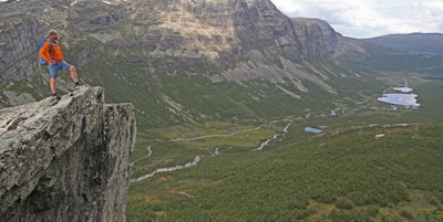 Mann på tuppen av en fjelltopp med utsikt over landskapet i Hemsedal