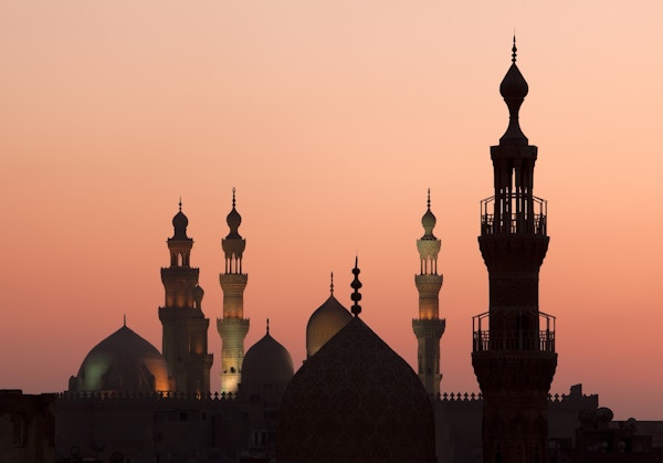Minareter og kupler mot en rosa himmel med solnedgang.