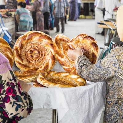To kvinner fotografert bakfra med tradisjonell usbekisk brødlavash på lokal basar, er et mykt flatbrød fra Midt-Asia (Usbekistan).