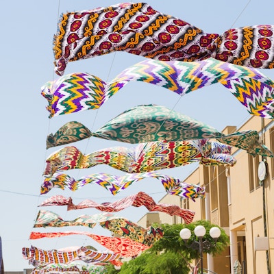Flerfargede tekstilmaterialer i silke som flagrer mot den blå himmelen i Margilan.