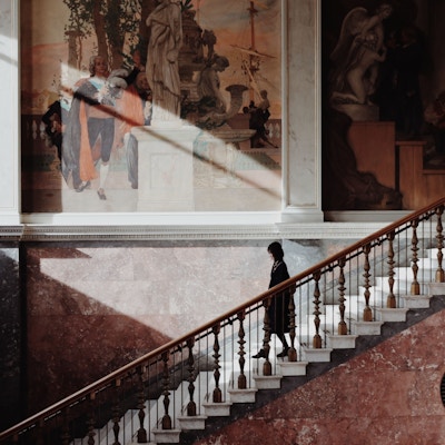 kvinne som går ned trapper foran store malerier