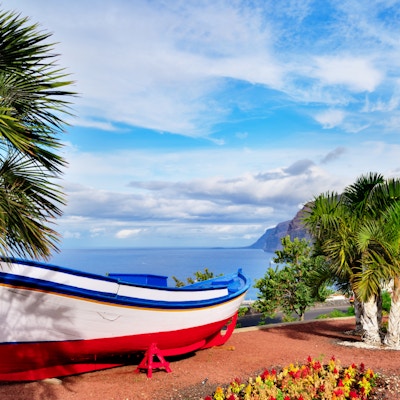 En fargerik malt fiskebåt utstilt nær havet i Los Gigantes, Tenerife, Kanariøyene, en naturskjønn utsikt over øya.