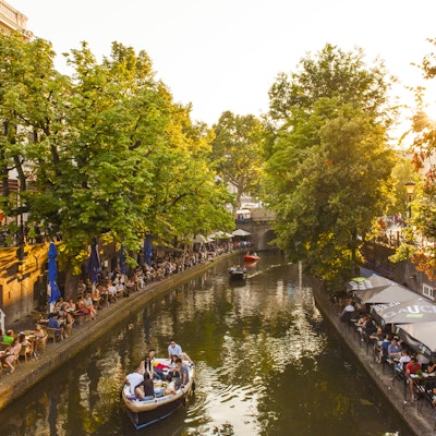 Båt på kanalen i Utrecht der bredden på begge sider er fylt med restauranter og mennesker