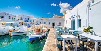 Havn med blå og hvite båter og sitteområde på land med hvite og blå møbler