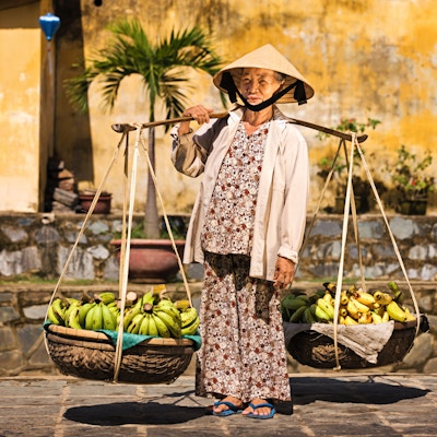 Vietnamesisk kvinne som bærer frukt til salgs i Hoi An, Vietnam.