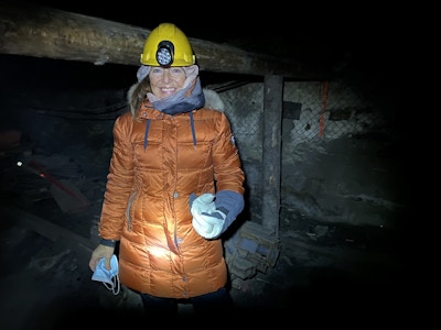 Kvinne med boblejakke og hjelm inne i ei gruve