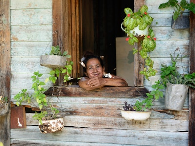 LAS CUEVAS, SANTIAGO DE CUBA, CUBA - 25. NOVEMBER: Kubansk kvinne smilende i huset sitt dekket med blomster på Cuba, Las Cuevas i 25. november 2016