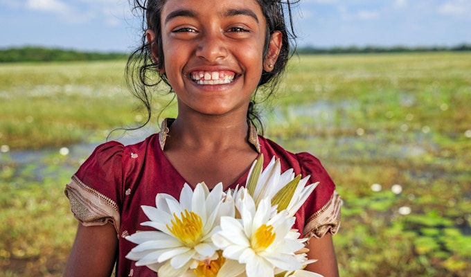Sri Lankesisk liten jente med lotusblomster i en innsjø nær Sigiriya, Ceylon.