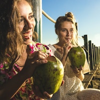 Jenter drikker kokosnøttvann ved Rio de Janeiro.