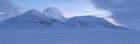 Landskapsbilde av snø og lave fjell med blåaktig lys