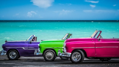 Tre amerikanske fargerikt konvertible veteranbiler parkert foran det karibiske hav på Malecon i Havana Cuba - Serie Cuba Reportage