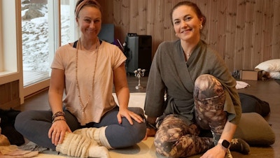 To damer sitter på yogamatte.