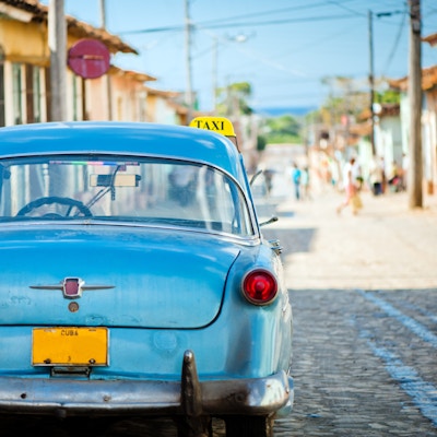Drosjebil i en trang gate i Trinidad, Cuba