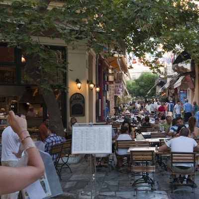 Mennesker som spiser mat på en taverna og turister som vandrer i gatene