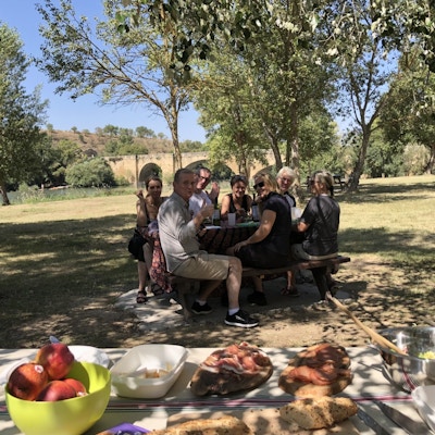mennesker rundt et bord som koser seg med god mat og drikke fra et piknikkbord