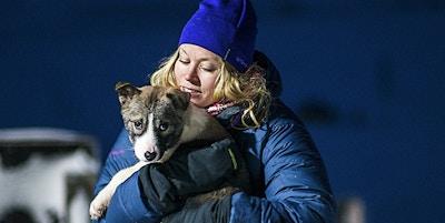 En kvinne som holder en hundevalp i polarnatten