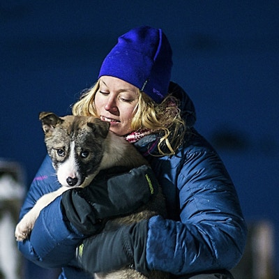 En kvinne som holder en hundevalp i polarnatten