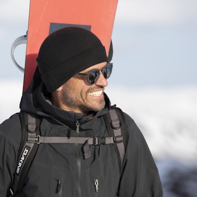 Smilende mann med snowboard på ryggen i Hemsedal Skisenter