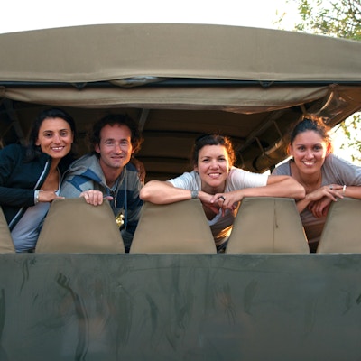 Fire glade smilende venner etter en vellykket dag med safari i Kruger-parken ved solnedgang