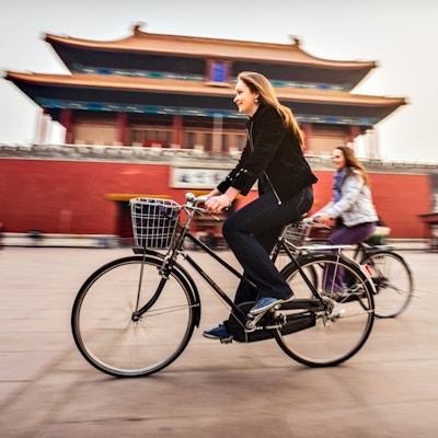 To kvnnlige turister på sykler foran Den forbudte by i Beijing.