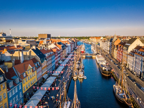 Urban kanal med seilskip, flankert av gater med danske flagg. Flyfoto.