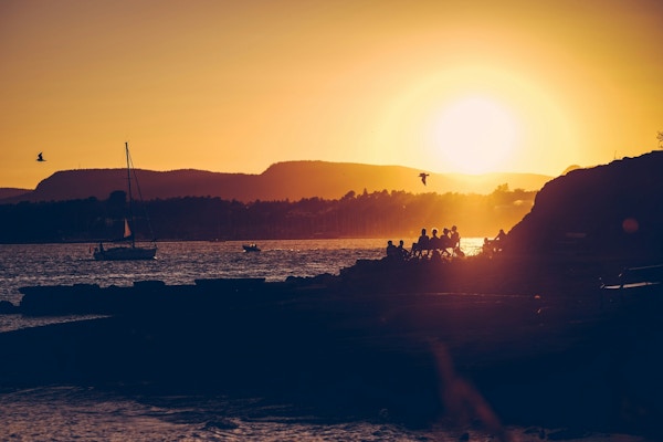 Seilbåt og mennesker på en øy i solnedgang
