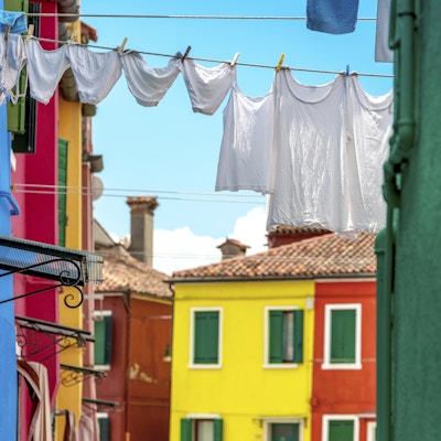 Klær som henger for å tørke i den fargerike øylandsbyen Burano nær Venezia, Italia.